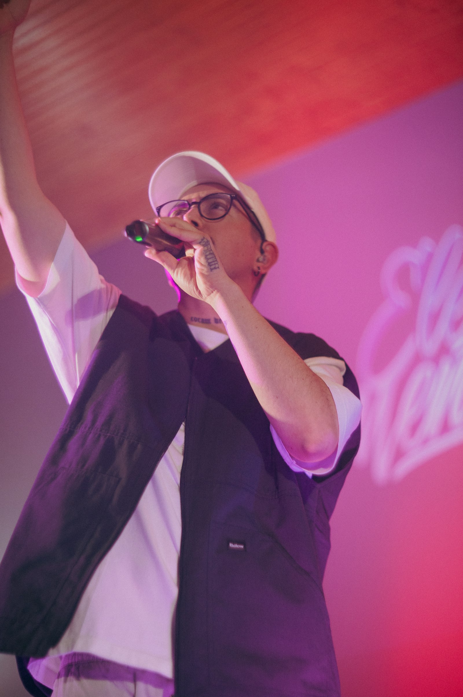 A rapper performing on stage with a microphone under warm lights.